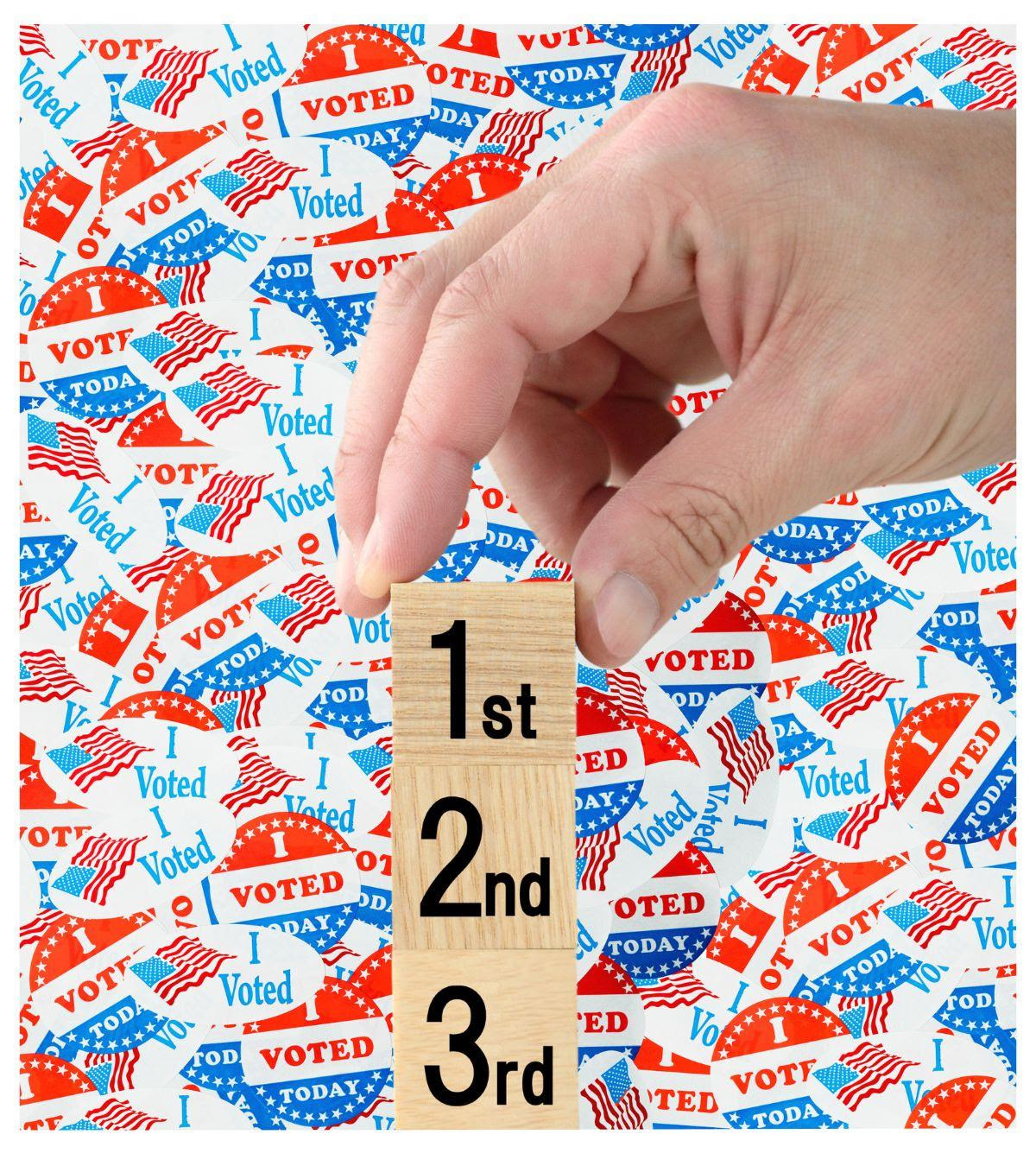ranked choice voting image with "1st", "2nd", "3rd" on scrabble tiles layed over image of layered graphic of "I Voted" stickers