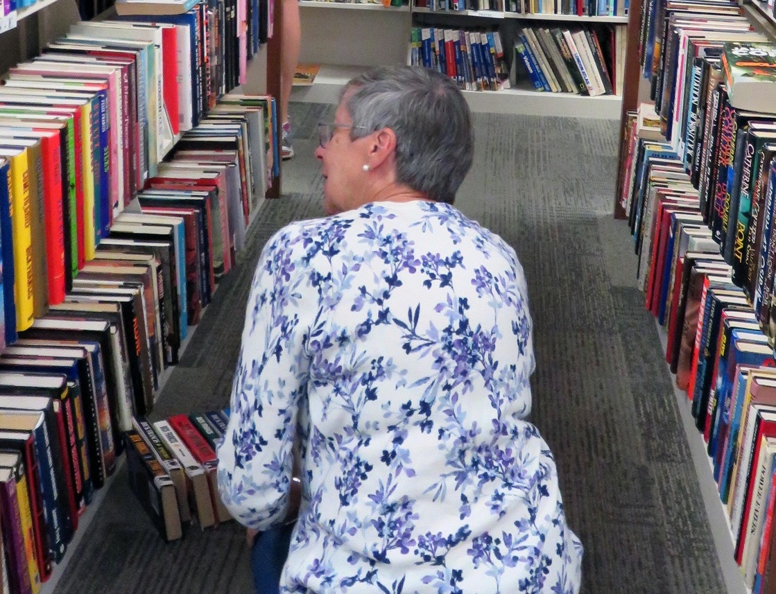 woman sitting on floor looking at library shelves
