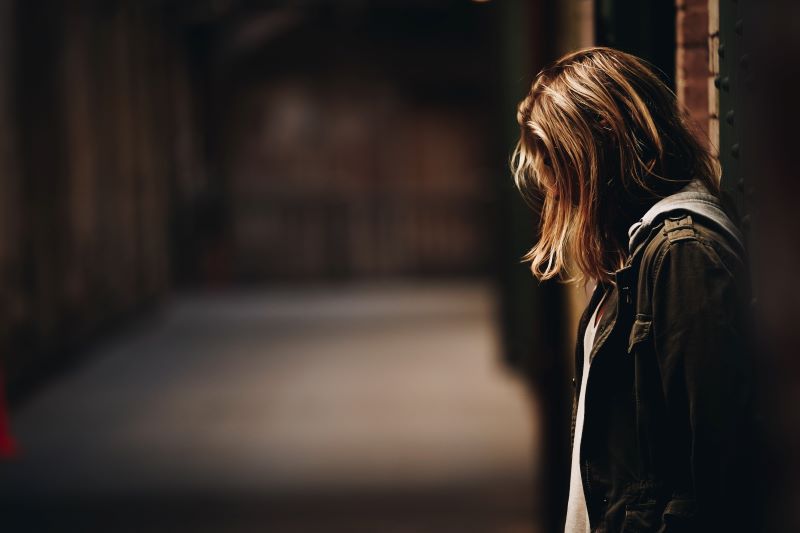 woman leaning against wall facing down