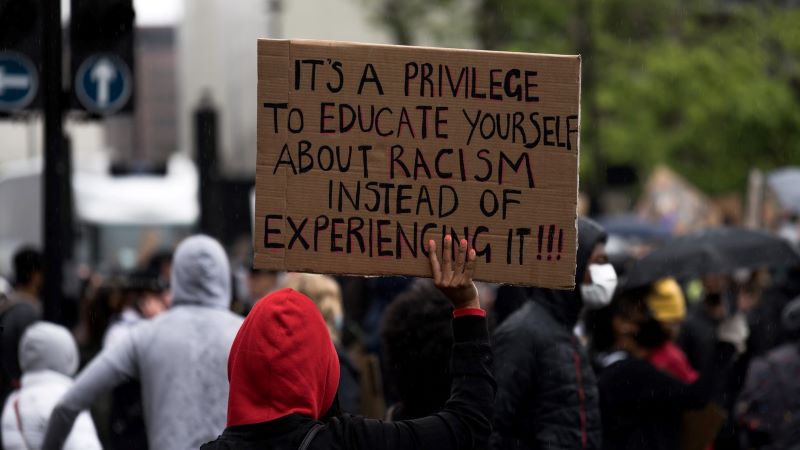 Protester holding sign "It is a privilege to educate yourself about racism..."