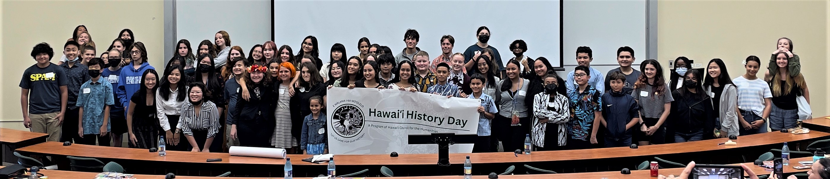 Participants smiling and holding banner that reads "Hawai`i History Day" with event logo