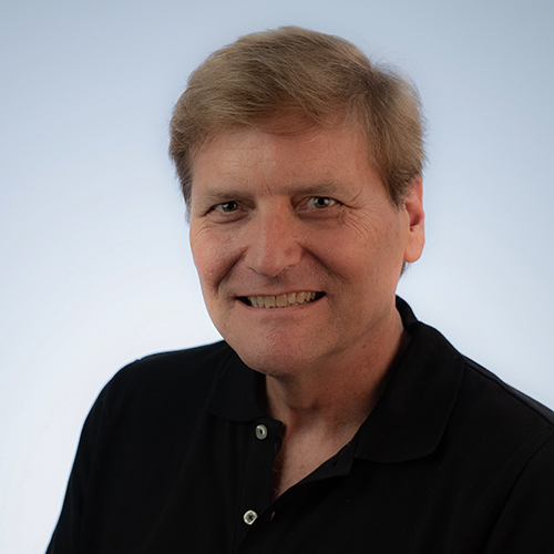 White male head shot. Blonde/red hair, black shirt and white background.