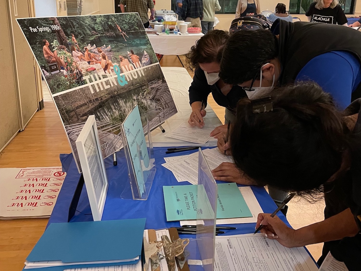 People signing petitions at display table with blue table cloth