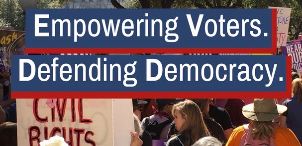 Empowering Voters. Defending Democracy. Marchers with signs. Empowering Voters. Defending Democracy.