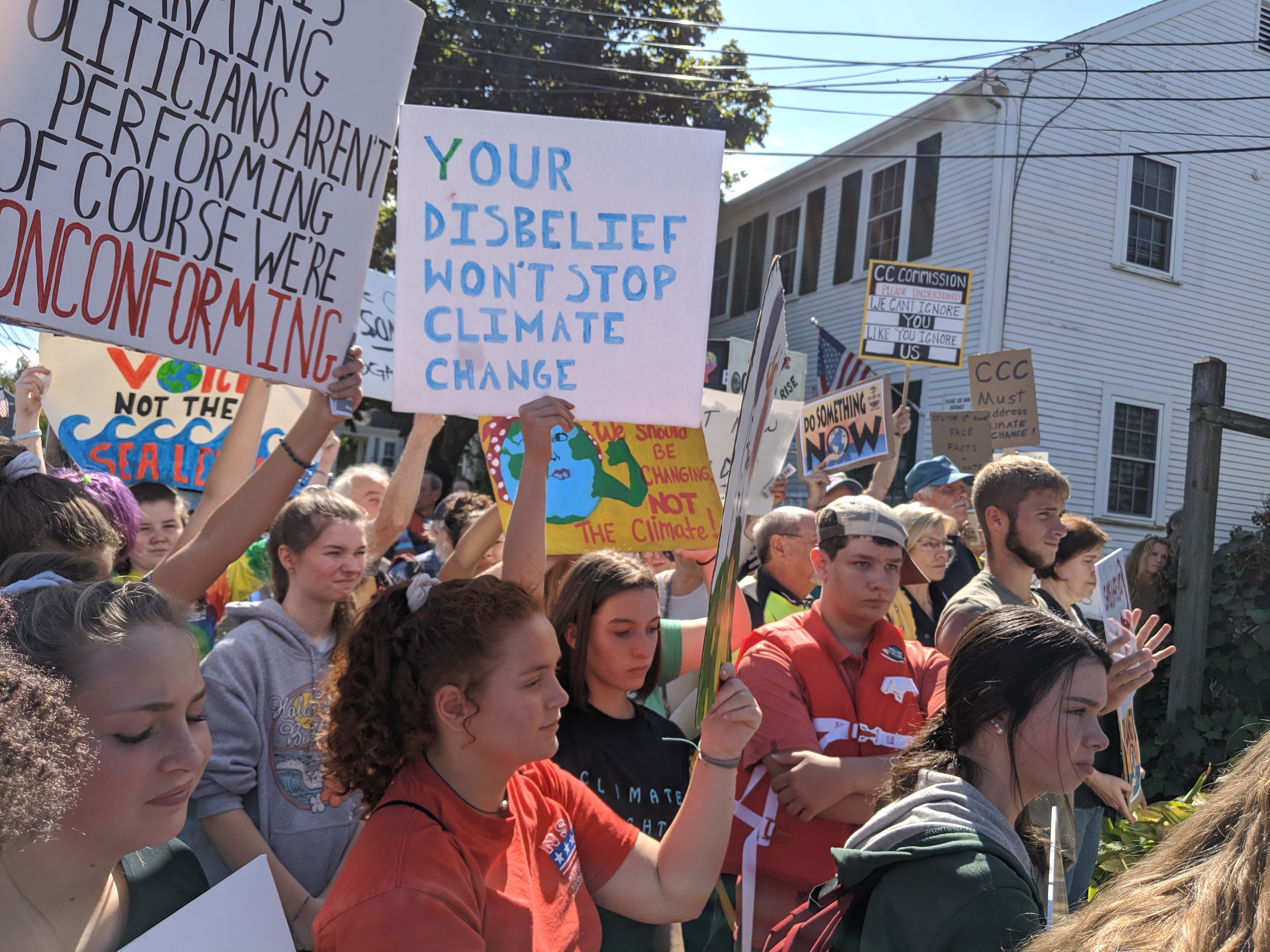 Students at the Dennis Glbal Climate March. sign reads "Your disbelief won't stop climate change".