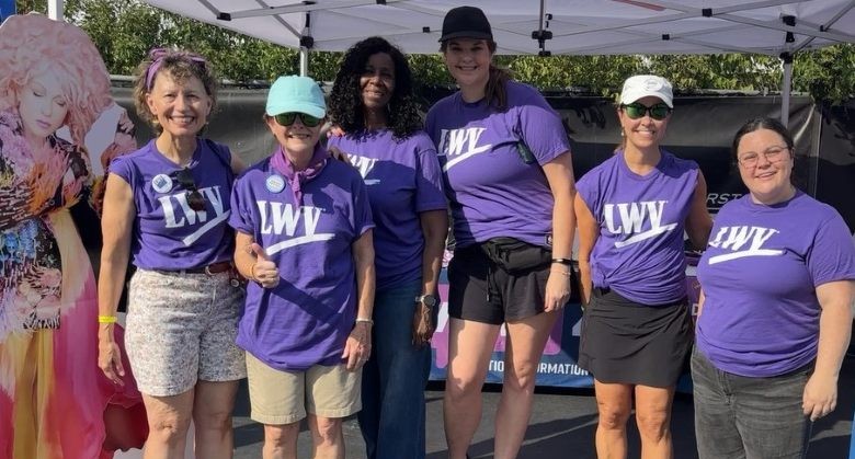 Six women in purple shirts, standing, smiling at camera