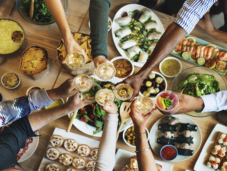 hands holding wine over lunch buffet