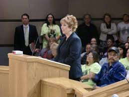 woman at podium with audience members behind her