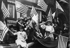 Historical photo: women and children wave USA flags while in motorcade parade