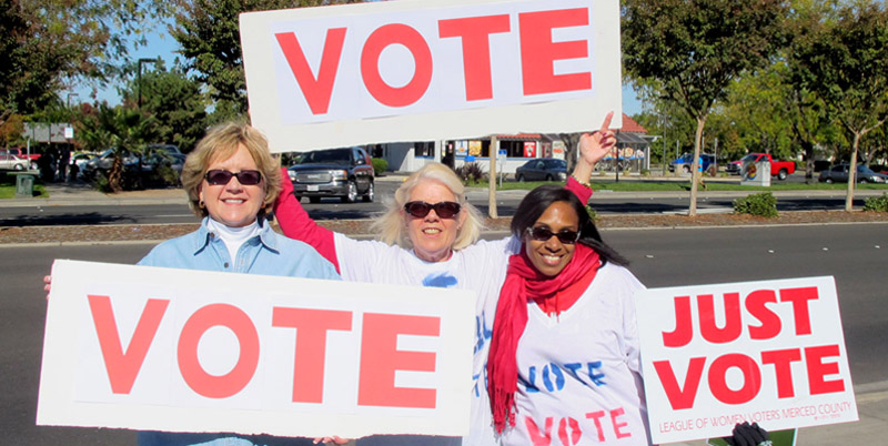 Three women holding vote signs