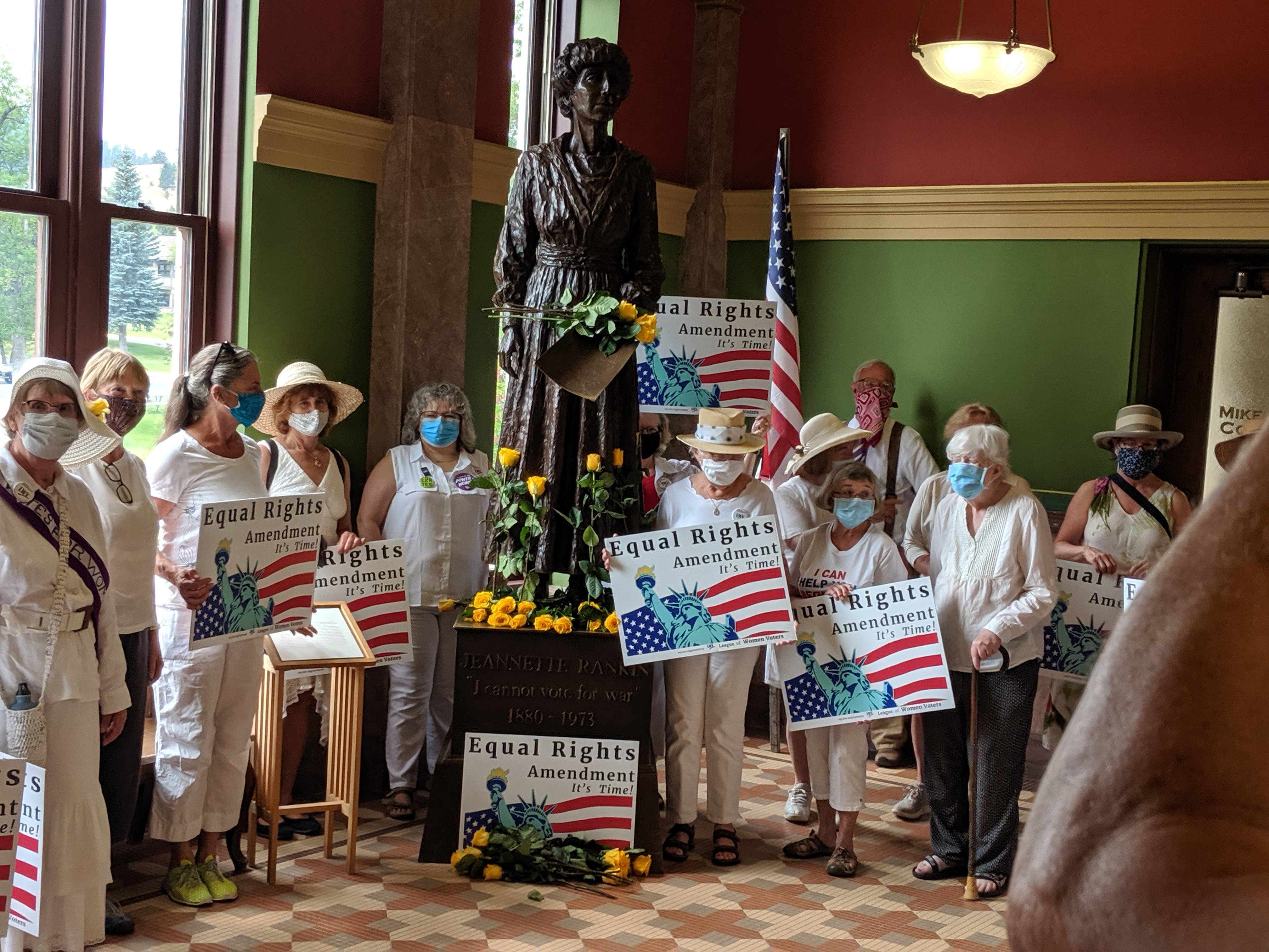 photo of people in white around statue of Jeannette Rankin in Montana Capitol