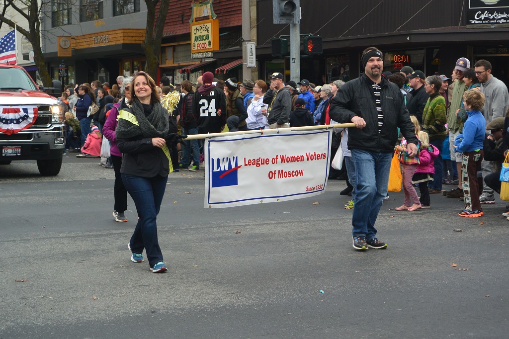 Man and women walking in parade holding League of Women Voters of Moscow sign