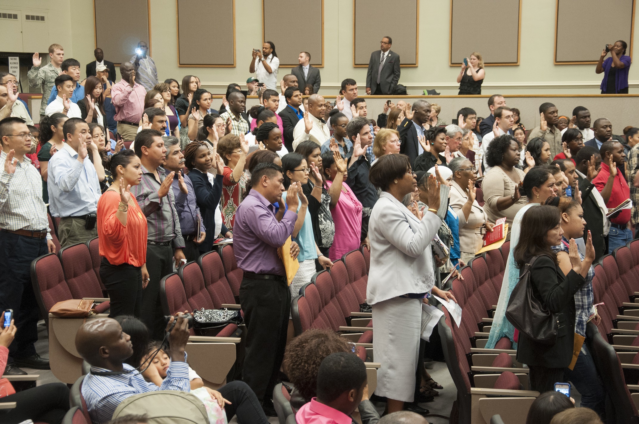 An auditorium full of people taking the new citizen's oath