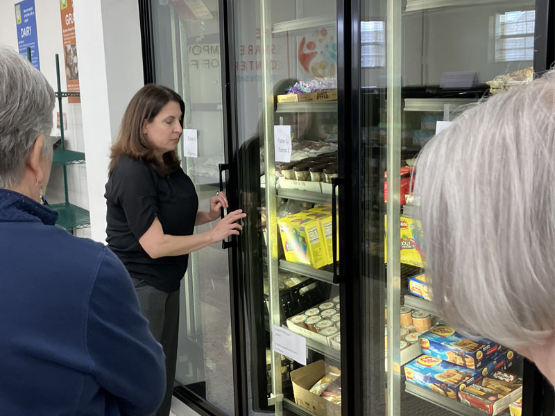 Women stands in front of freezers. 