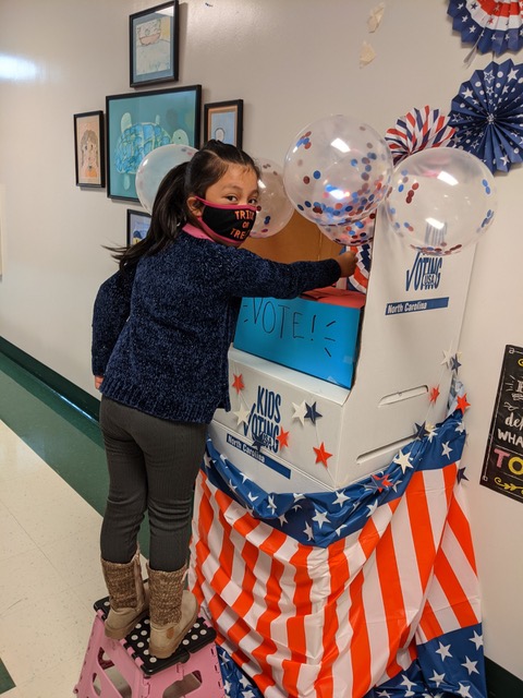 Young student submits ballot in mock election at school 