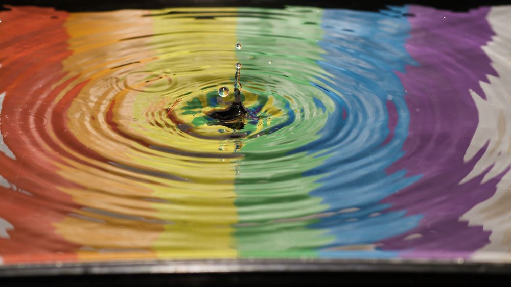 time lapse photography of water ripple with pride colors