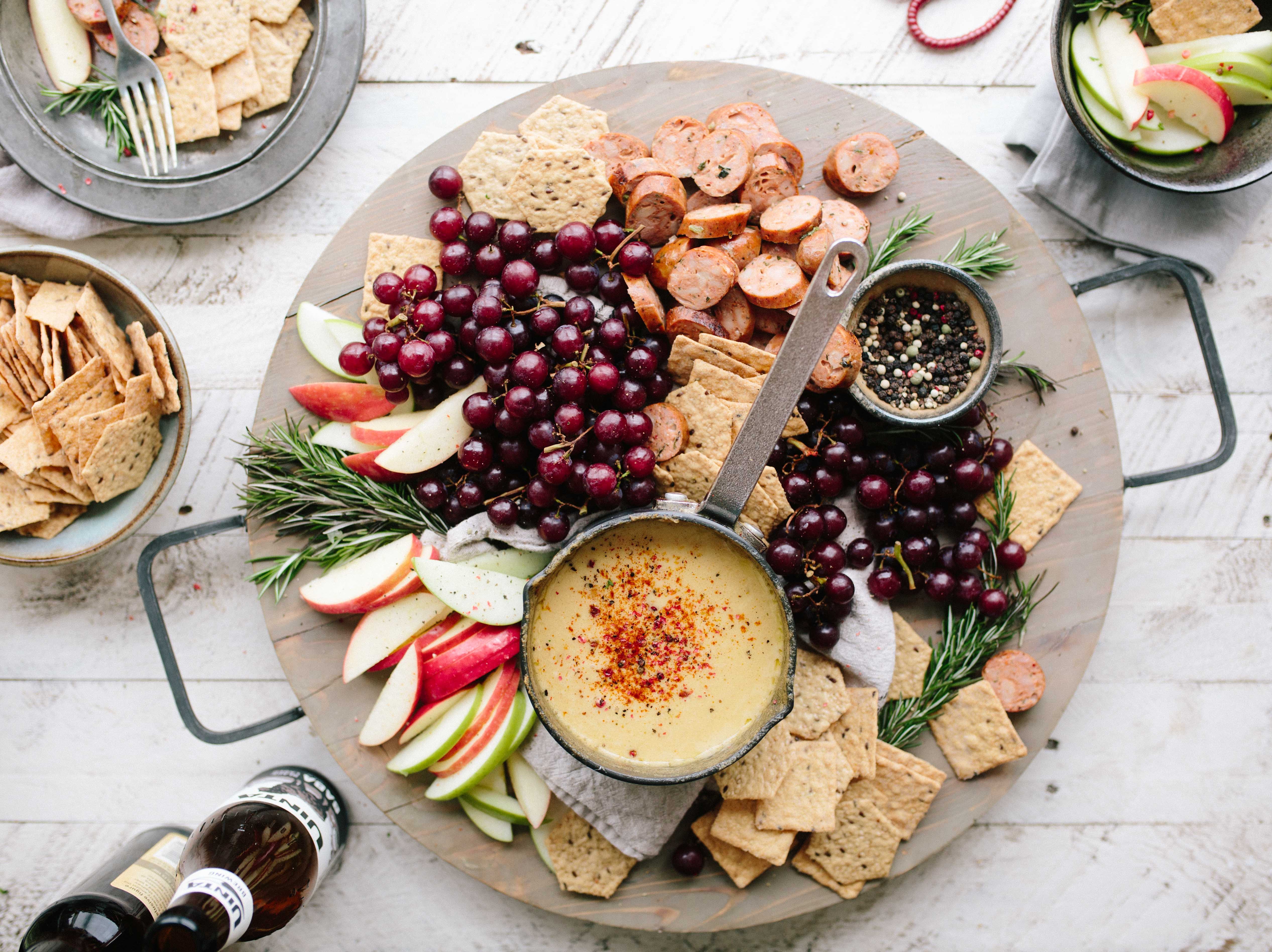 An image of a platter of crackers, fruit, and dips as for a party.