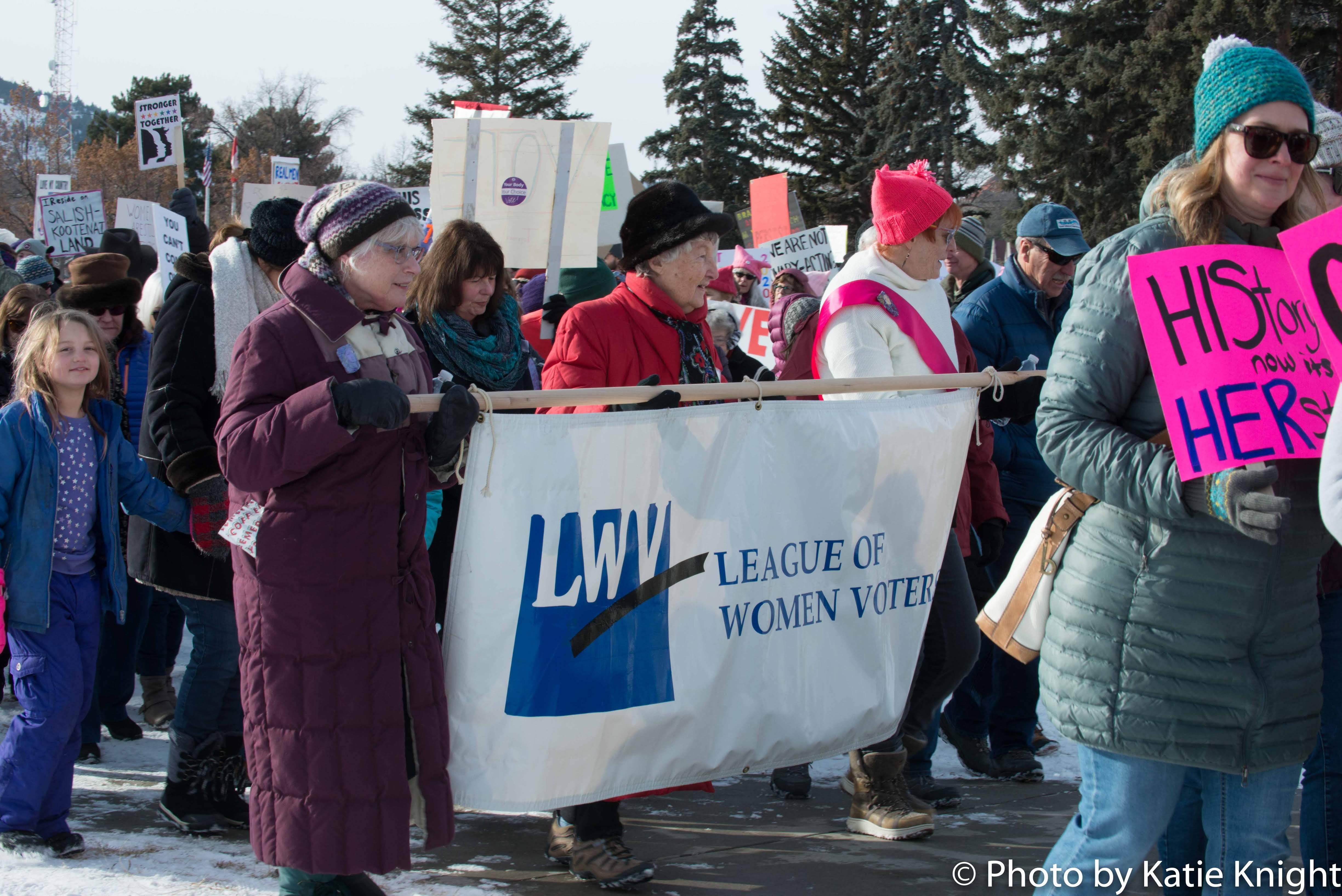 image of three women holding League of Women Voters banner and marching 