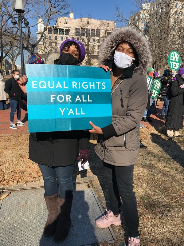 Two women at a rally holding a sign that says Equal Rights for All Y'all 
