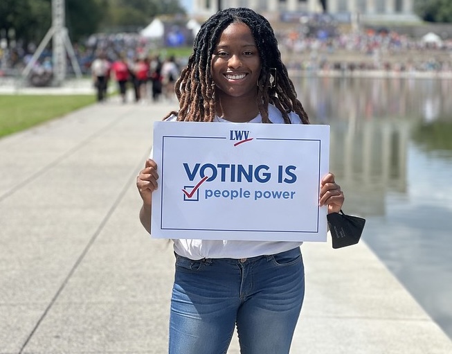 Women holding sign Voting is People Power
