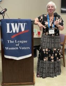 LWVMO President Marilyn Monroe by a podium with a League banner