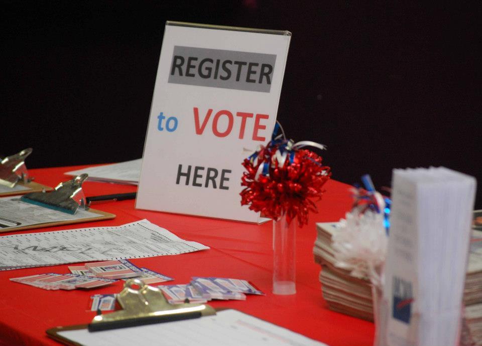 Photo of Voter Registration Table with "Register to Vote Here" sign