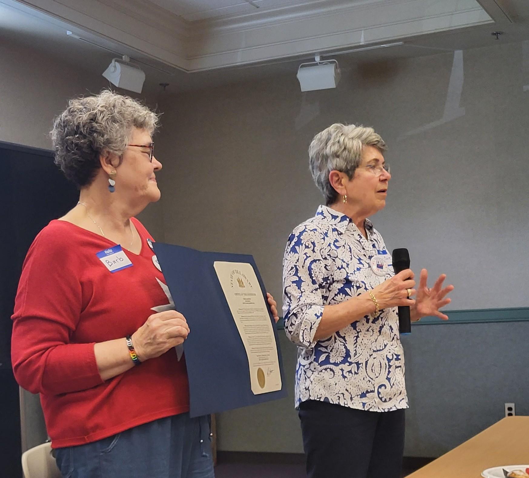 Pres. Barb Hedges-Goettl stands as Sue Claire Harper for the participants. 