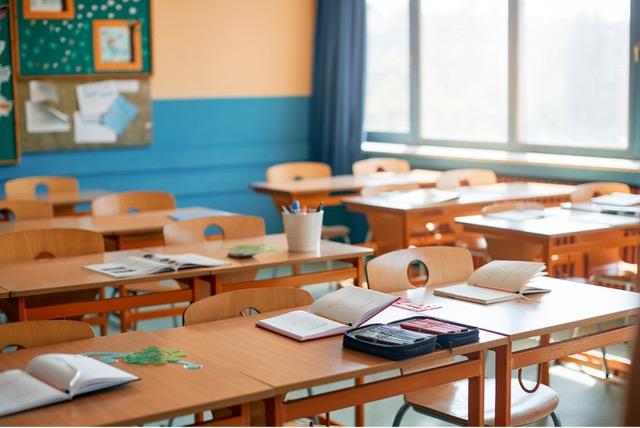 Photo shows an empty classroom of desks and chairs