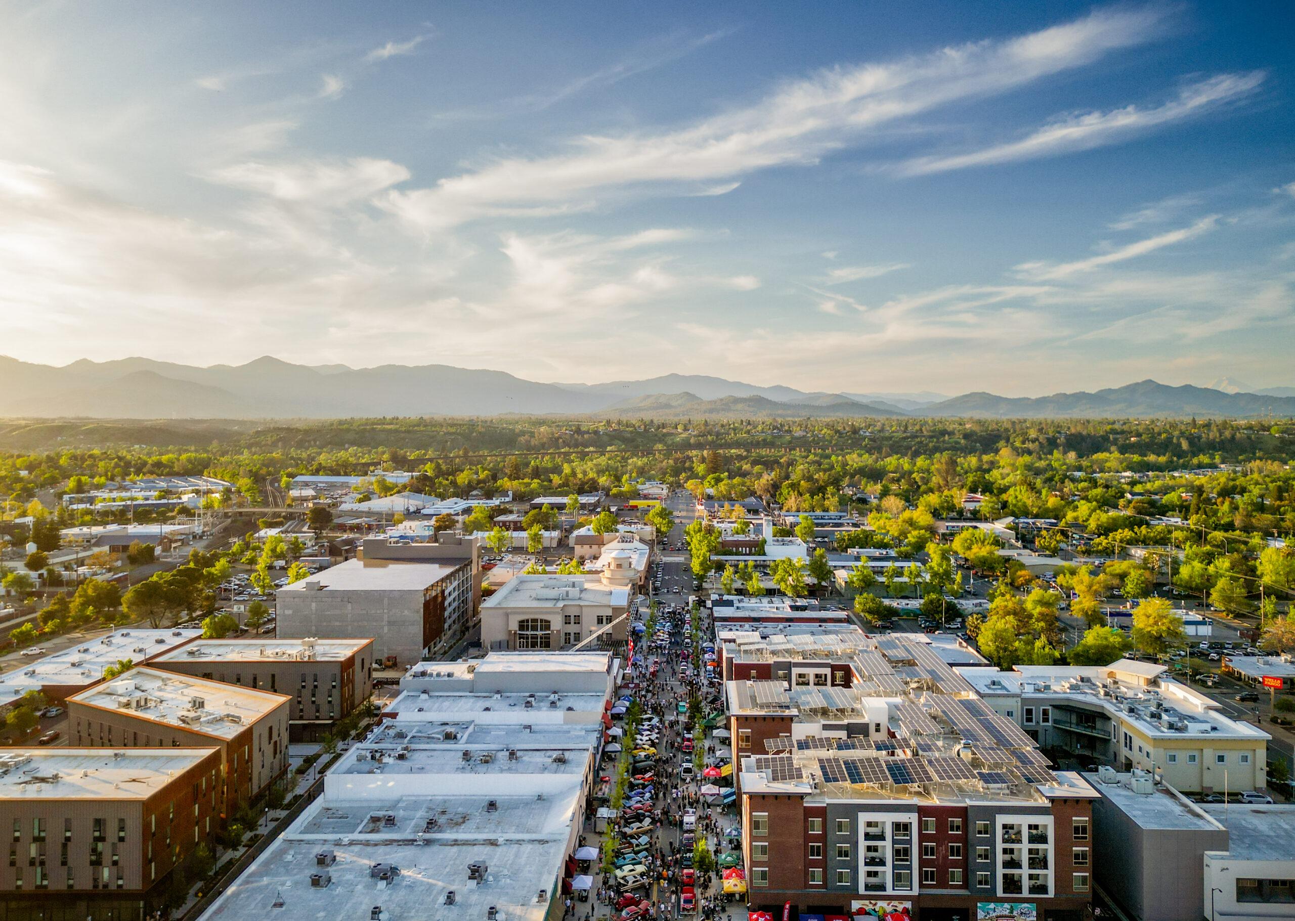 Aerial view of downtown Redding with surrounding trees and mountains in the distance.
