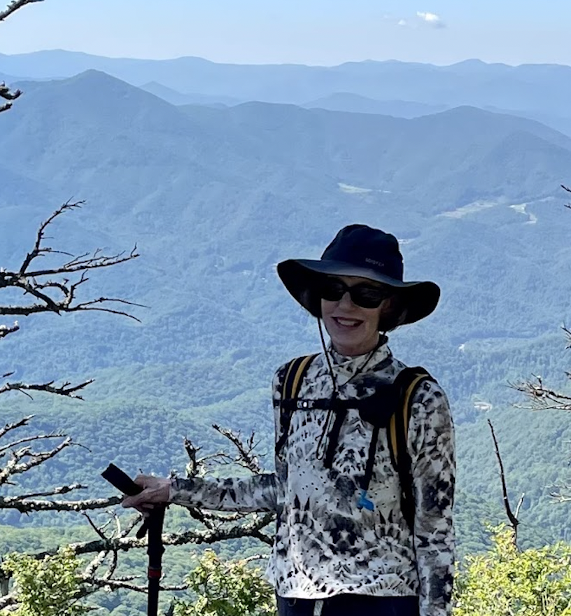 Woman in wide brim hat and sunglasses with mountains in the background