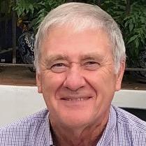 Headshot of a smiling man with gray hair and a light purple shirt