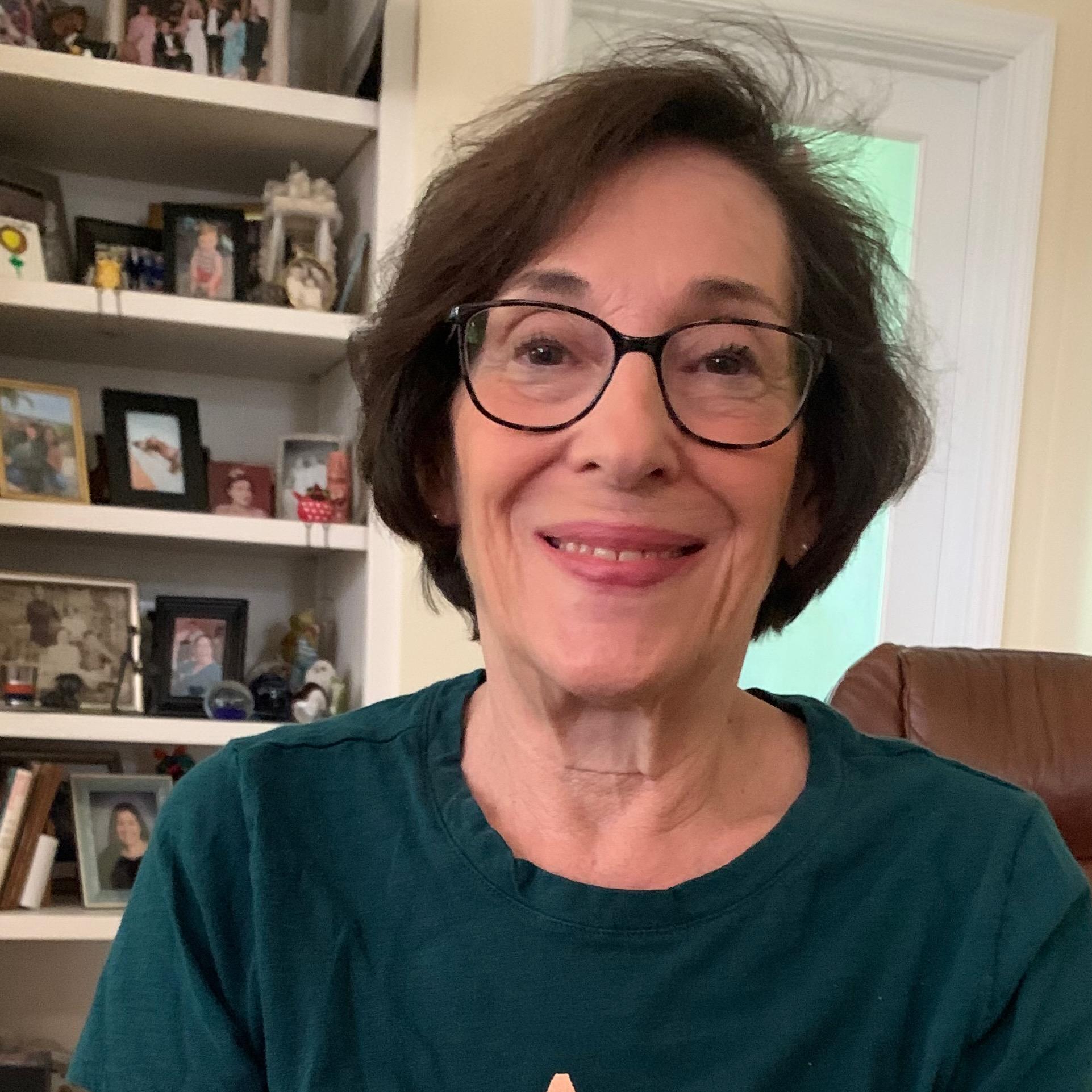 Head and shoulders photo of a smiling woman with glasses and short brown hair