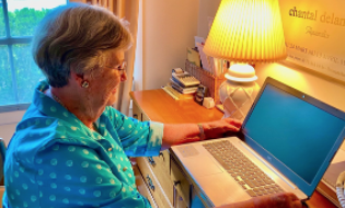 Woman sitting at desk facing an open laptop computer