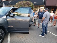 Attendees surround the Rivian R1T owned by a local resident.