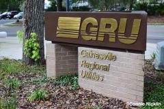 Gainesville Regional Utilities (GRU) Sign brown background with gold logo and brick base with gold letters