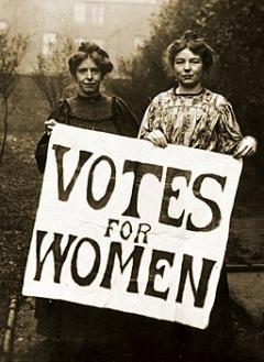 black and white photo of two women from the early 1900's holding a sign that say Votes for Women