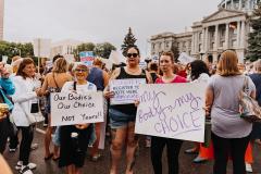 photo of women holding signs that say: "Our bodies, our choice - not yours!"