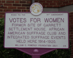 "VOTES FOR WOMEN Former Site of Garrett Settlement House (etc.)" photo of white commemorative sign with purple lettering