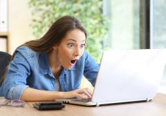 Photo of woman looking at computer with surprise