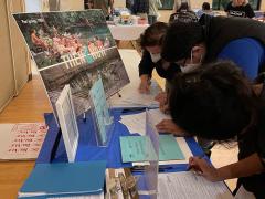 People signing petitions at display table with blue table cloth