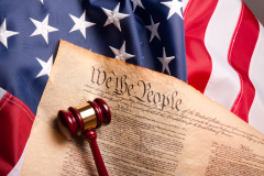 Image of american flag with a gavel and the beginning of the U.S. Constitution