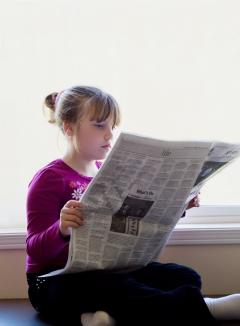 young girl reading newspaper
