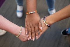 Three hands touching with bracelets spelling vote.