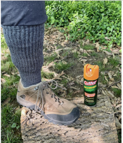 sock pulled up over pants leg alongside can of insecticide
