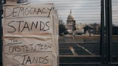 Democracy Stands Handwritten Sign with Capitol Building in the Background