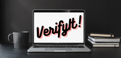Image of a desk with laptop displaying "VerifyIt!"