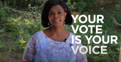 A woman standing behind white text that reads "Your vote is your voice" 