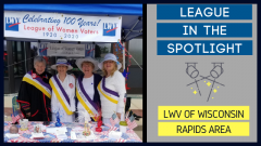 Four of the League of Women Voters of Wisconsin Rapids members at the 100 Year celebration. The accompanying image is a picture of two spotlights and the words "League in the Spotlight: LWV of Wisconsin Rapids Area"
