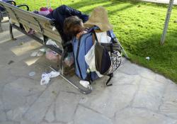 shopping cart with personal possessions next to park bench