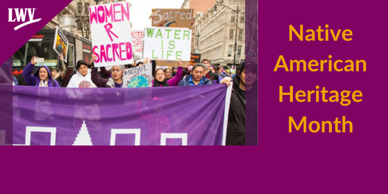 Native american heritage month image of native american women marching with signs . one sign reads women are sacred.  other sign reads water is life